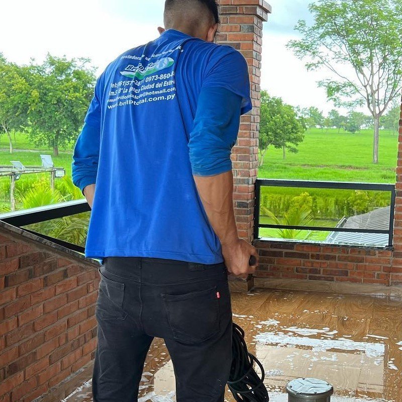 Técnico uniformado de Brillo Total en terraza de residencia realizando limpieza de piso